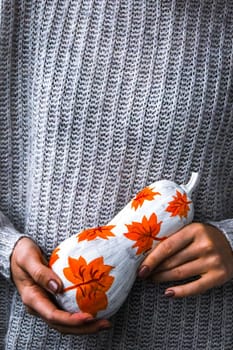 Female hands holding painted pumpkin. Fall decoration. Autumn harvesting. Do it yourself. Thanksgiving concept. Diy. Sweater