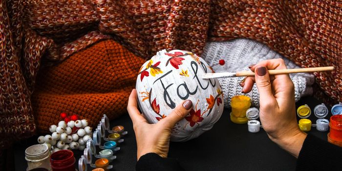 DIY. Do it yourself. Woman paints thanksgiving decorations on orange pumpkin for Halloween. Autumn harvest. Sweater home cozy. Paintbrush