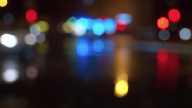 Blurred night city traffic lights. Rainy. Reflection of the colorful lights on the wet asphalt. City background