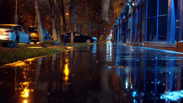 Autumn rain in the night city. Street lights reflected in the puddles on the pavement