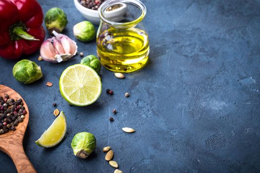 Ingredients for cooking. Olive oil in glass jar, wooden cooking spoon, spices, red bell pepper, lime, brussels sprout, garlic, colourful seasonings. Cooking ingredients background. Space for text