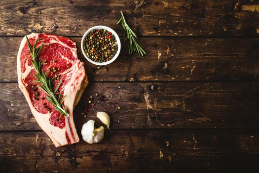 Raw marbled meat steak, pepper, herbs, garlic, old wooden background. Space for text. Beef Rib eye steak ready for cooking. Top view. Copy space. Ingredients, meat roasting. Ribeye meat steak. Closeup