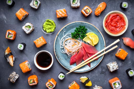 Japanese sushi on a rustic dark background. Sushi rolls, sashimi, nigiri, maki, pickled ginger, wasabi, soy sauce. Sushi set on a table. Top view. Asian or Japanese food. Sushi restaurant concept