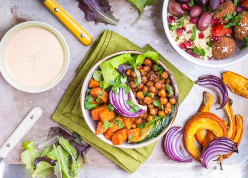 Healthy vegetarian salads with vegetables, sweet potato, falafel, bulgur. Healthy buddha bowl salads, sauce. Vegan/vegetarian food. Healthy lunch/dinner. Salad in bowl on table. Top view. Ingredients