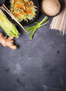 Ingredients for making chinese dinner: wheat noodles, rice, napa cabbage, ginger, green onion. Asian cooking ingredients. Top view. Preparing healthy asian meal with vegetable salad. Space for text