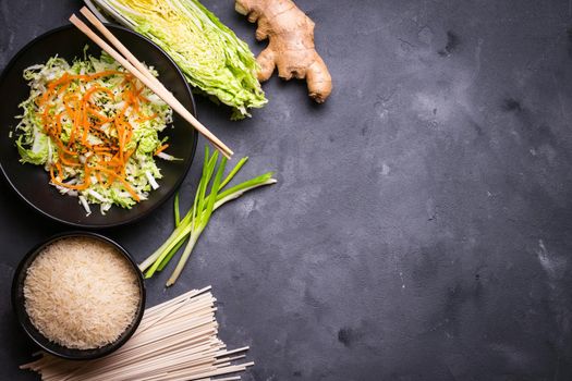 Ingredients for making chinese dinner: wheat noodles, rice, napa cabbage, ginger, green onion. Asian cooking ingredients. Top view. Preparing healthy asian meal with vegetable salad. Space for text