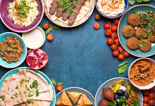 Middle eastern or arabic dishes and assorted meze on concrete rustic background. Meat kebab, falafel, baba ghanoush, hummus, sambusak, rice, tahini, kibbeh, pita. Halal food. Space for text. Top view