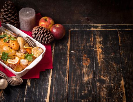 Roasted chicken. Christmas food background. Rustic celebration table with roasted chicken, vegetables, apples, decorated with candles, vintage cutlery. Christmas/Thanksgiving dinner. Space for text