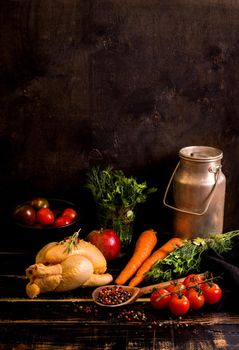 Raw whole chicken ready for cooking. Chicken with vegetables, herbs and spices on a black rustic wooden background. Diet or clean healthy eating concept. Ingredientd for cooking