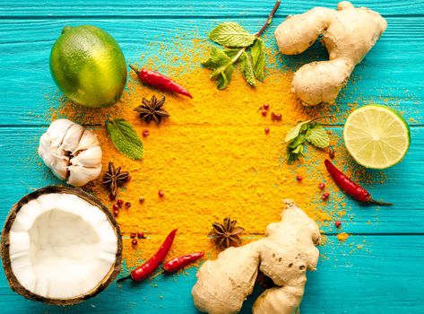 Thai food background. Ingredients for making thai food. Coconut, ginger, hot pepper, lime, curry, herbs, spices. Thai cuisine ingredients on blue wooden background. Space for text. Top view. Close-up