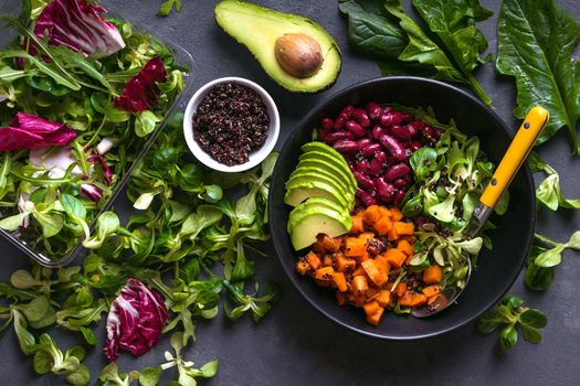 Quinoa salad in bowl with avocado, sweet potato, beans, herbs, spinat on concrete rustic background. Quinoa superfood concept. Clean healthy detox eating. Vegan/vegetarian food. Making healthy salad