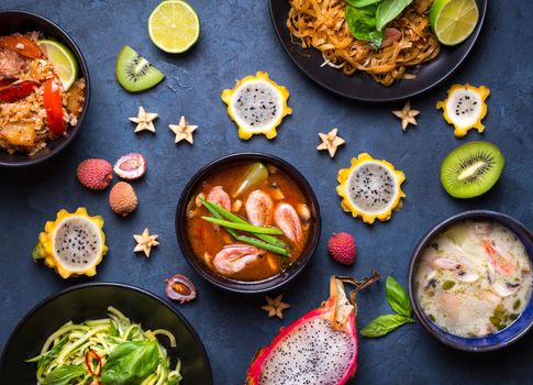 Assorted Thai food. Traditional dishes of Thai cuisine. Tom yum, tom kha gai, pad thai noodles, thai fried rice with pork and vegetables khao phat mu, green papaya salad som tam, thai fruits. Top view