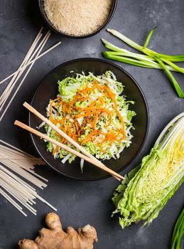 Asian or chinese salad with napa cabbage, carrot, black sesame seeds. Ingredients for making chinese dinner: wheat noodles, rice, napa cabbage, ginger, green onion. Asian cooking ingredients. Top view