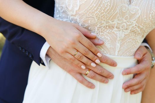 bride and groom holding hands with wedding rings