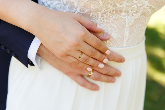 bride and groom holding hands with wedding rings