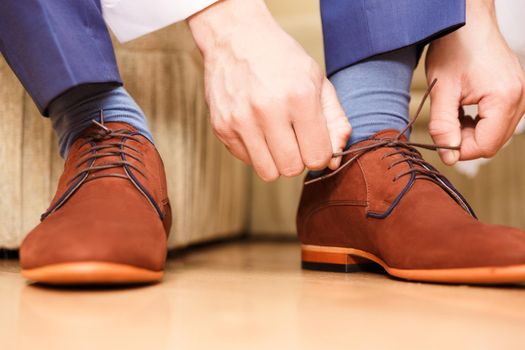 groom putting his wedding shoes. Hands of wedding groom getting ready in suit