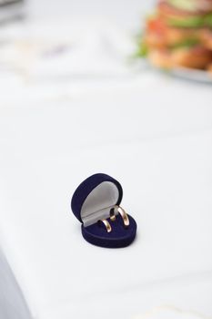 Wedding rings in blue box on a tabl