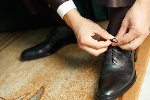 Groom dresses and binds shoes before the wedding