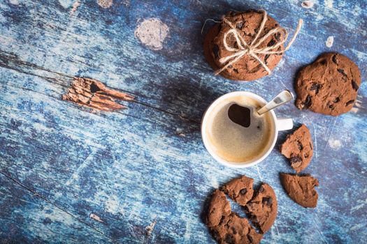 Cup of fresh hot coffee, chocolate cookies on old rustic blue wooden table. Vintage background. Space for text. Morning coffee. Warm coffee, dessert for lunch. Espresso, white cup. Top view. Close up