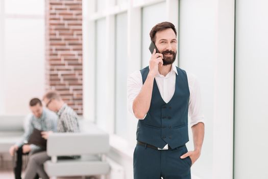 smiling businessman talking on smartphone in office.people and technology