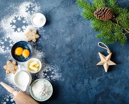 Christmas/New Year food background. Baking ingredients, snowflake cookies, Christmas decoration. Making festive New Year sweets. Flour, rolling pin, gingerbread, milk, eggs. Space for text. Top view