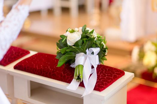 Wedding bouquet laying on bench in church during the wedding ceremony