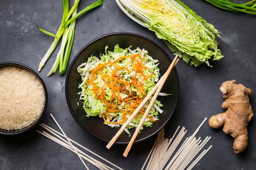 Asian or chinese salad with napa cabbage, carrot, black sesame seeds. Ingredients for making chinese dinner: wheat noodles, rice, napa cabbage, ginger, green onion. Asian cooking ingredients. Top view