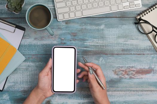 Overhead view woman using smart phone on wooden background. Flat lay.