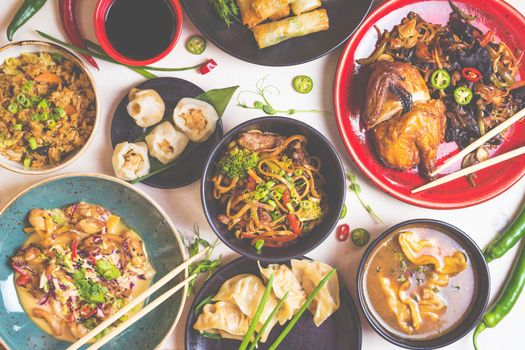 Assorted Chinese food set. Chinese noodles, fried rice, dumplings, peking duck, dim sum, spring rolls. Famous Chinese cuisine dishes on white table. Top view. Chinese restaurant concept. Toned image