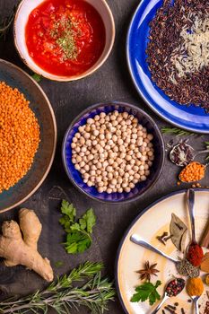 Table served with traditional for asian or eastern cuisine food. Cereal grains, beans, spices on colorful plates. Lentil, basmati and wild rice mix, chick-pea, tomato chutney, pita. Ingredients for indian or eastern food