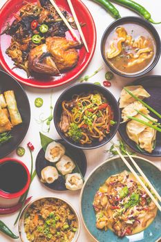 Assorted Chinese food set. Chinese noodles, fried rice, dumplings, peking duck, dim sum, spring rolls. Famous Chinese cuisine dishes on white table. Top view. Chinese restaurant concept. Toned image