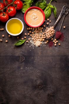 Hummus ingredients. Chickpea, tahini, olive oil, sesame seeds, sumac, herbs on dark rustic wooden background. Space for text. Set of ingredients for making hummus. Middle eastern cuisine. Top view