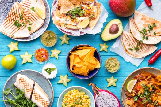 Assorted mix of traditional Mexican food. Different Mexican dishes table. Cheese nachos, tacos, guacamole, quesadilla, burrito, fajitas, tortilla chips, Mexican fruits. Tex-Mex cuisine. Mexico style
