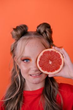 sweet joyful brunette girl female with cropped slice of grapefruit near skin face on orange background. tasty juicy fruit. Tropical citrus fruits, Healthy food. weight loss.