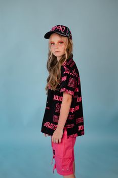 stylish teenage girl. tween school girl wearing pink fashion clothes on blue background. long hair and freckles.