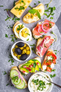 Assorted healthy sandwiches set background. Sandwich bar or buffet. Ciabatta sandwiches with dips, fish, cheese, meat, vegetables. Top view. Making sandwiches concept. Lunch time snacks. From above