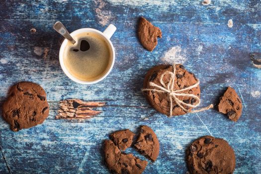 Cup of fresh hot coffee, chocolate cookies on old rustic blue wooden table. Vintage background. Morning coffee. Warm coffee, dessert for lunch. Espresso in white cup. Top view. Close up. From above