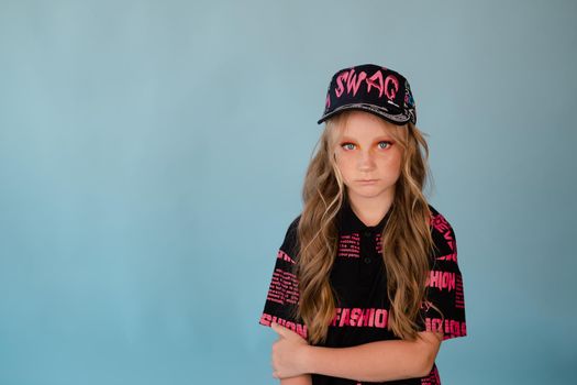 fashion teenager portrait. tween school girl with orange makeup wearing pink stylish cool clothes on blue background.