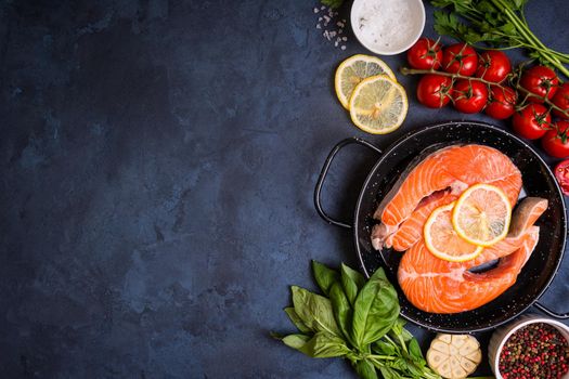 Raw fresh fish with vegetables ready to cook. Raw salmon steak with lemon and spices in a pan. Ingredients for cooking on a concrete background. Space for text. Diet and healthy food. Fish background