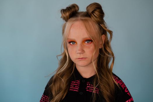 stylish teenage girl. tween school girl wearing pink fashion clothes on blue background. long hair and freckles.