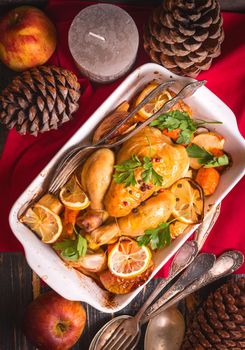 Roasted chicken. Christmas food. Rustic celebration table with roasted chicken, vegetables, apples, decorated with candles, vintage cutlery. Christmas/Thanksgiving dinner. Festive dinner. Top view