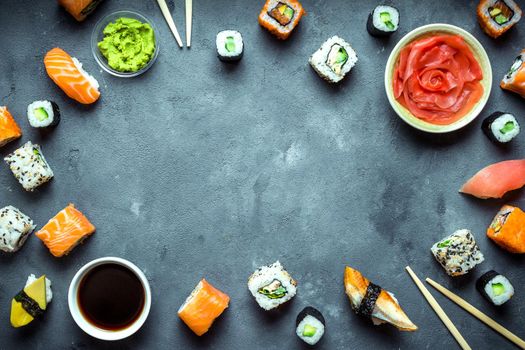 Japanese sushi on a dark background. Sushi rolls, nigiri, maki, pickled ginger, wasabi, soy sauce. Sushi set on a table. Space for text. Top view. Sushi background. Asian or Japanese food frame. Toned