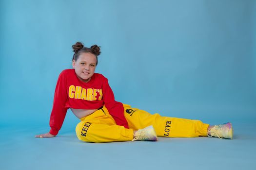 beauty portrait of stylish teenage girl in fashionable bright clothes. tween wearing red and yellow clothes on blue background. fashion portrait. two topknots. bright orange make up.