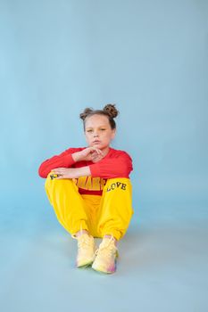 teenage girl in fashion stylish bright clothes. little lady in red and yellow on blue background. makeup and hairdo.