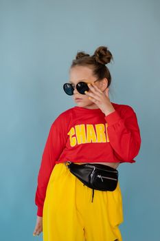 teenage girl in fashion stylish bright clothes. little lady in red and yellow on blue background. makeup and hairdo.