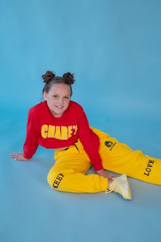 teenage girl in fashion stylish bright clothes. little lady in red and yellow on blue background. makeup and hairdo.