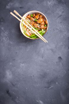 Asian style noodles with teriyaki chicken, vegetables and green peas pods. Noodles in bowl on rustic concrete background. Chinese/thai/japanese style stir fry noodles. Space for text. Top view