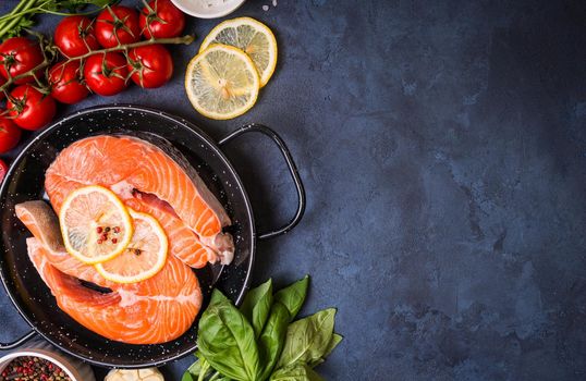 Raw fresh fish with vegetables ready to cook. Raw salmon steak with lemon and spices in a pan. Ingredients for cooking on a concrete background. Space for text. Diet and healthy food. Fish background