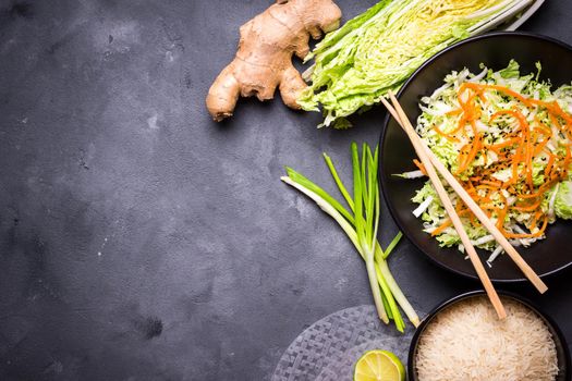 Ingredients for cooking vietnamese dinner: rice paper, rice, napa cabbage, ginger, green onion, salad. Asian cooking ingredients. Top view. Making vietnamese vegetable spring rolls. Space for text