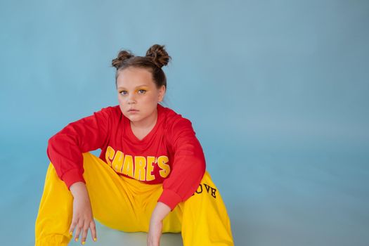 teenage girl in fashion stylish bright clothes. little lady in red and yellow on blue background. makeup and hairdo.